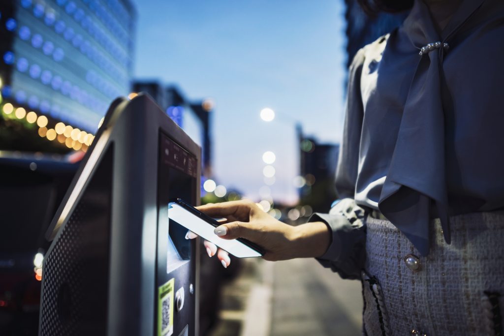 Asian business woman in the city making mobile payment for parking place