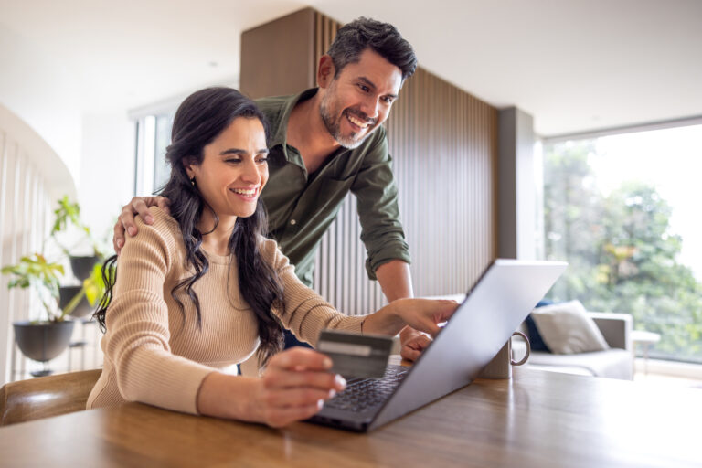 Happy couple shopping online from home and paying by card