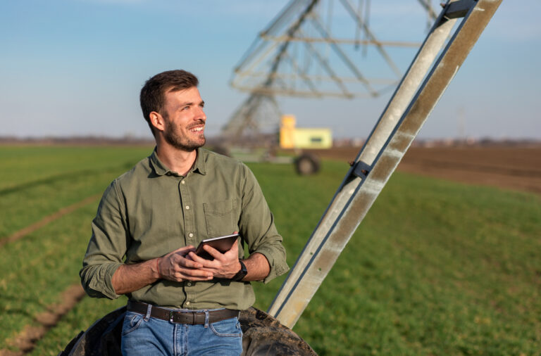 Young farmer standing in wheat field and setup irrigation system on tablet.
