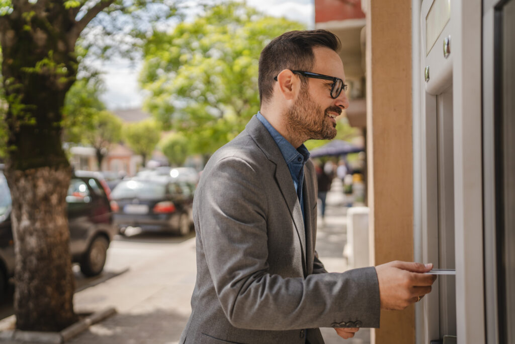 Adult caucasian man stand and hold credit card use cash machine
