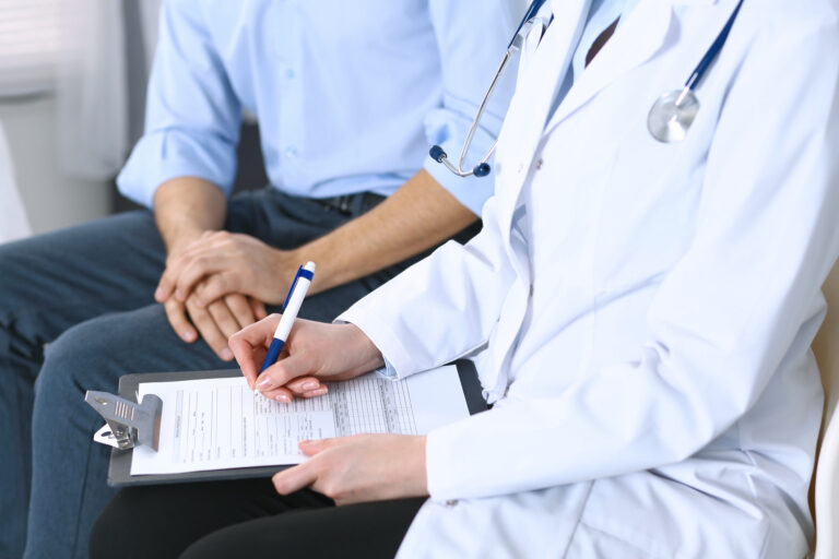 Female doctor holding application form while consulting man patient in hospital. Medicine and healthcare concept