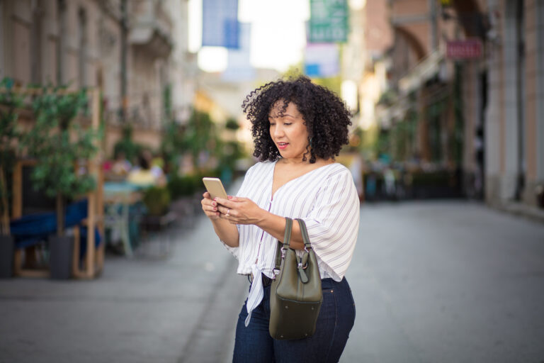 Woman standing on the street and using mobile.