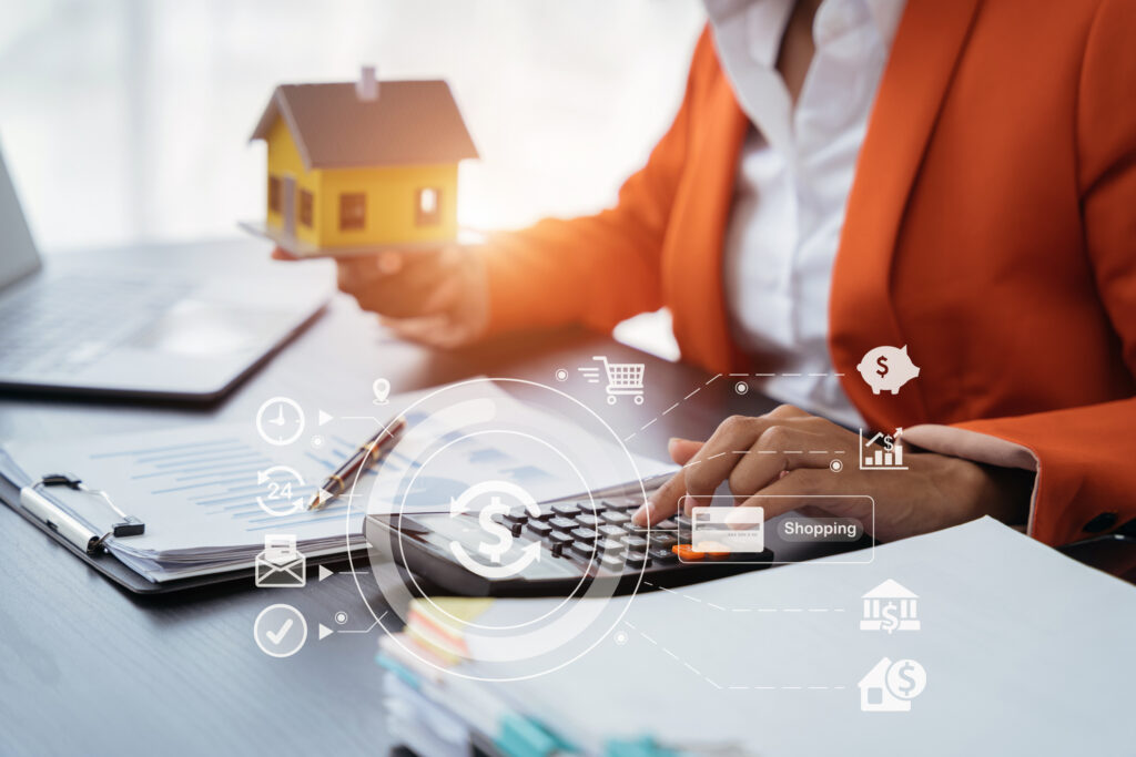 home loan officer uses a calculator with a house plan.